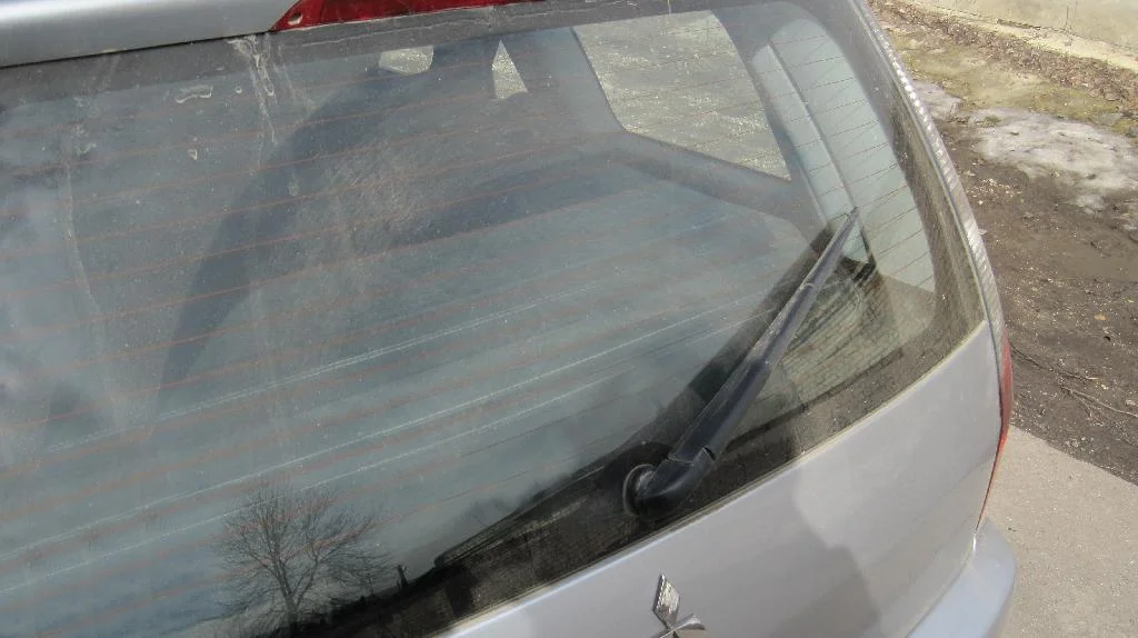Крышка багажника Mitsubishi Lancer IX Wagon, стекло пыльное и грязное, щетка стеклоочистителя стоит в неправильном положение.