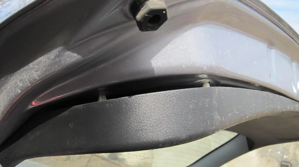 Пластиковая накладка крышки багажника Mitsubishi Lancer IX Wagon в процессе снятия. Защелка начинают общёлкиватся.
