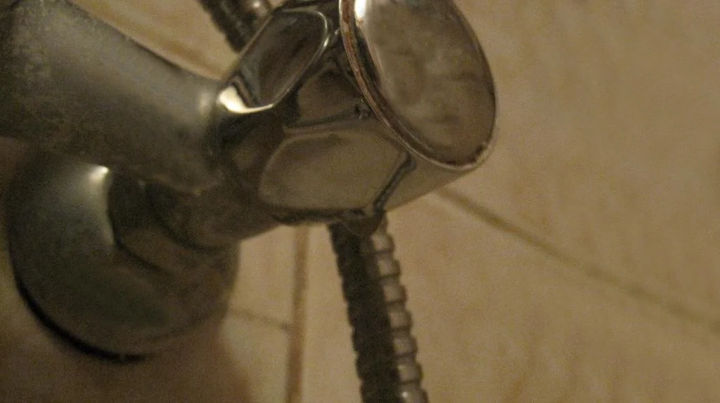 Смеситель для ванны IDDIS установлен, из кран-буксы капает вода и стекает по ручке.