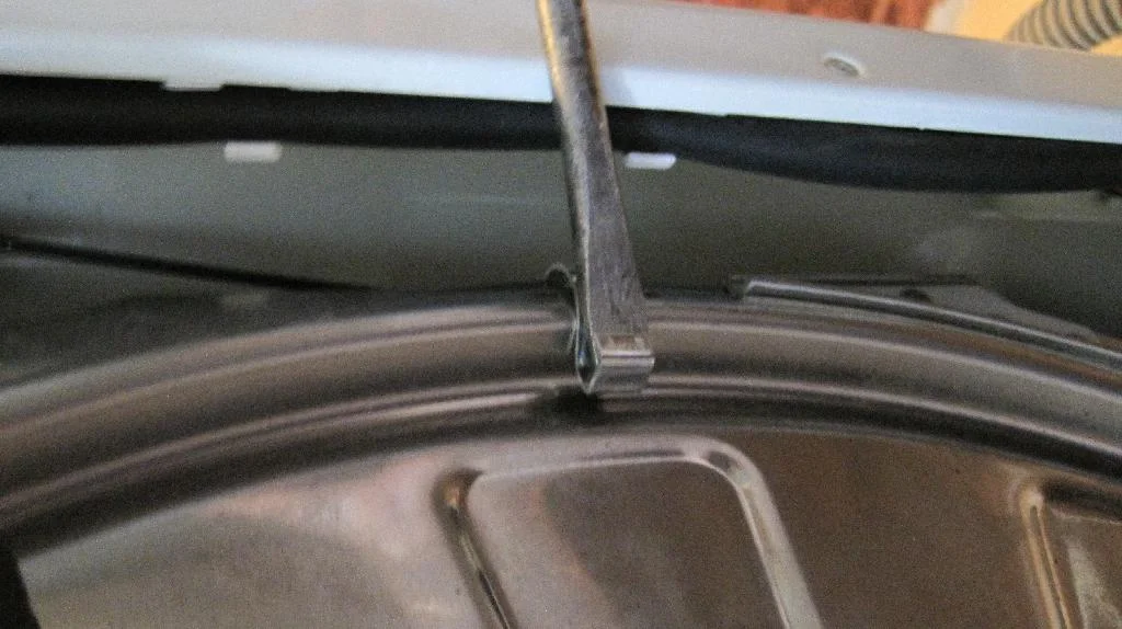 Снятие зажимок боковой крышки бака стиральной машины ARDO TL1000X при помощи отвертки, металлических зажим поддет отверткой