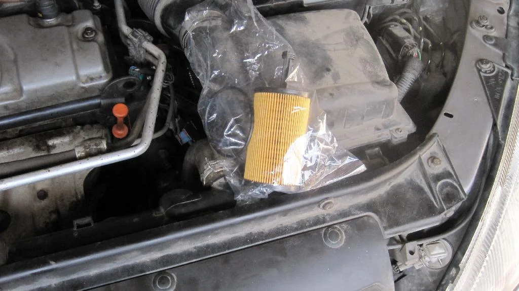 Новый масленый фильтр двигателя TU3JP лежит под капотом автомобиля Peugeot 206