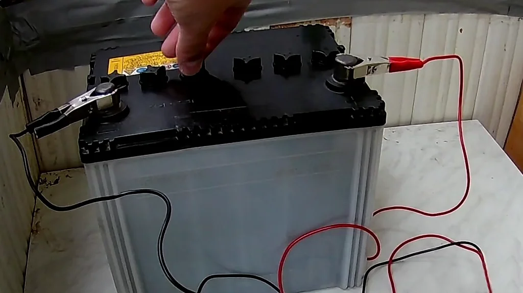 Свинцово-кислотная батарея с неплотно закрытыми пробками и подключенным зарядным устройством