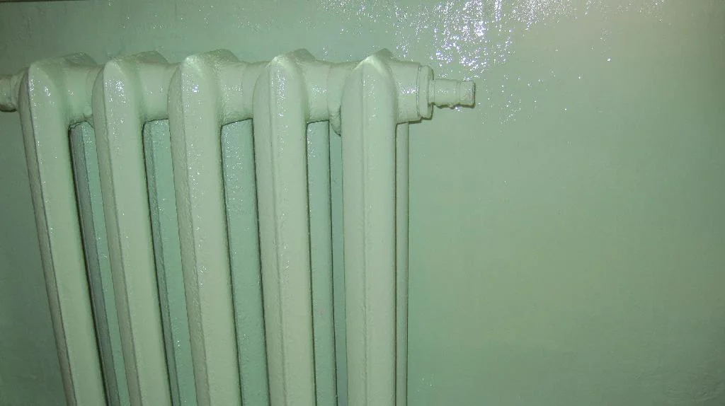 Радиатор отопление и ниша под подоконником покрашены в салатовый цвет. Малярный скот на шаровом кране радиатора отопления.